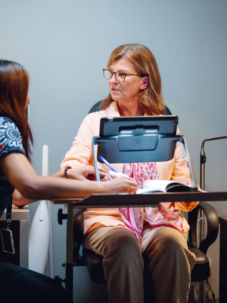 A Vision Australia team member assisting a client during an eye health appointment.